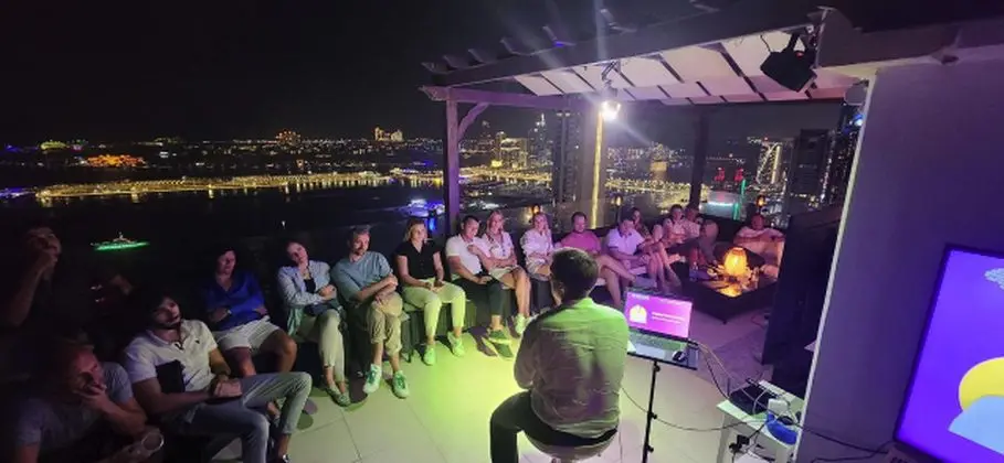 YDN Tech Guild rooftop session at night with an audience seated facing a speaker and the Dubai skyline behind