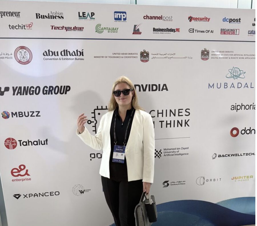Anastasia Yushkina at an AI summit in Abu Dhabi in front of a sponsor wall